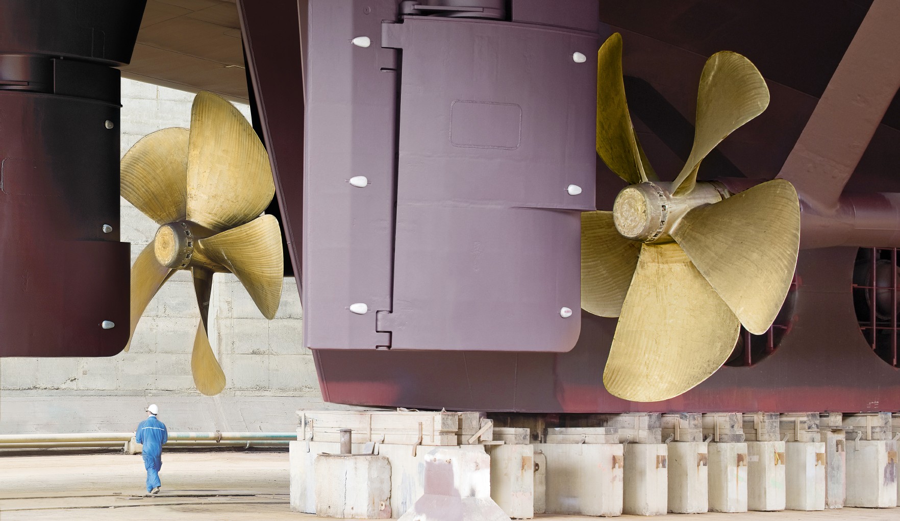 Close-up of vessel propellers at the shipyard with a worker in the back